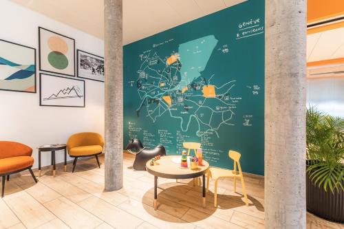 a room with a green wall with a table and chairs at Appart'City Collection Genève Aéroport - Vernier in Geneva