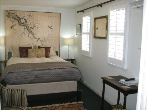 a bedroom with a bed and a table and windows at Three Chimneys Bed and Breakfast Boutique Guest House in Albany