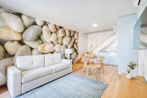 a living room with a white couch and a rock wall at Casa do Calhau - 1 bedroom apartment sleeps 4 in Câmara de Lobos