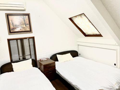 two beds in a room with white walls at 新宿へ行く便利の一軒家 in Tokyo