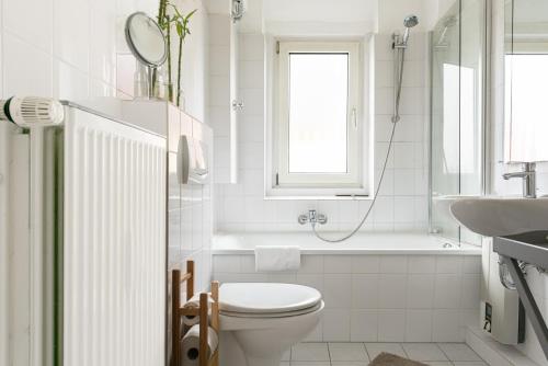 ein weißes Bad mit einem WC und einem Waschbecken in der Unterkunft Haus MeerZeit Whg.2 in Cuxhaven