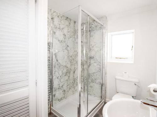 a white bathroom with a shower and a toilet at Angel Cottage in Weymouth