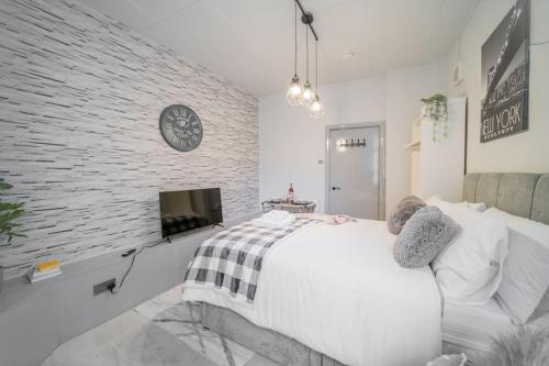 Un dormitorio con una pared de ladrillo blanco y una cama en Cozy Studio in Shepherds Bush en Londres