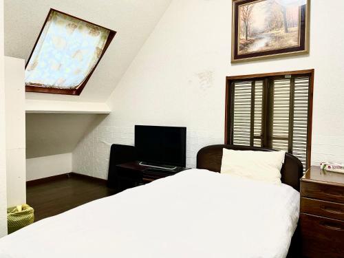 a bedroom with a bed and a desk with a television at 新宿へ行く便利の一軒家 in Tokyo