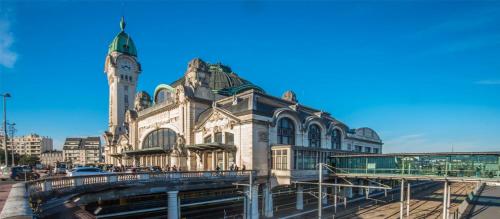 ein großes Gebäude mit einem Uhrturm in einer Stadt in der Unterkunft Le Théodore Bac-Spacieux T2 - Coup de coeur en face de la gare des Bénédictins in Limoges