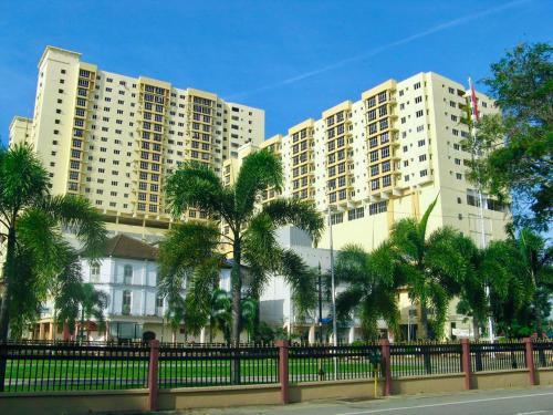 two tall buildings with palm trees in front of a fence at N'dnie Homestay Pelangi Mall Condominium in Kota Bharu