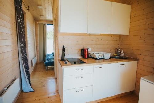 a kitchen with white cabinets and a sink in a room at Liepa SaulesKempings in Mērsrags