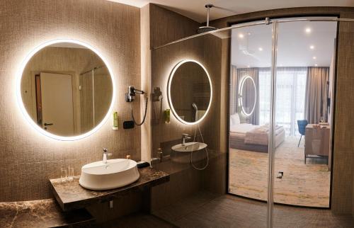a bathroom with a sink and a shower with two mirrors at Crona SPA Karpaty in Skhidnitsa