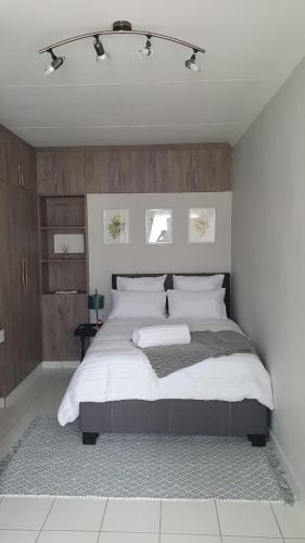 ein Schlafzimmer mit einem großen Bett mit weißer Bettwäsche in der Unterkunft Refresh Cottage near OR Tambo Airport & Greenstone in Edenvale