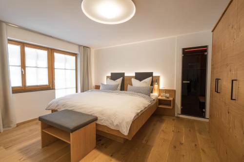 a bedroom with a large bed with a stool and a television at Landhaus Wiederkehr in Oberstdorf