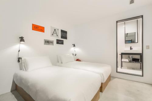 two white beds in a room with a mirror at ART'OTEL Ximending TAIPEI in Taipei