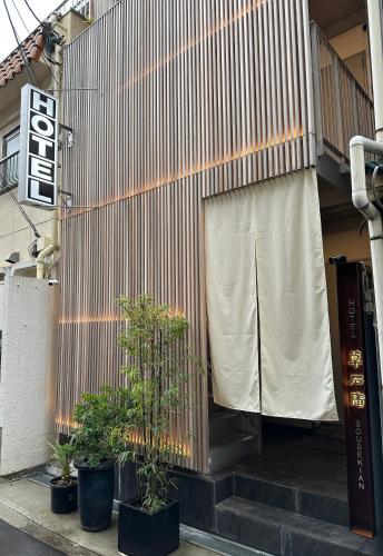 a building with a fence and some plants on the steps at Hotel 草石庵 in Osaka