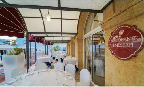 un ristorante con tavoli bianchi e sedie bianche di LEUCA TWENTY ROOMS a Leuca