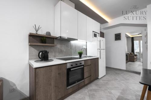 a kitchen with white cabinets and a stove top oven at Adelle Apartments, The Luxury Suites in Thessaloniki