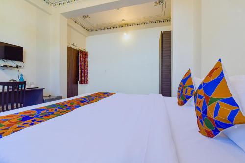 a bedroom with a white bed with colorful pillows at FabExpress Achrol Palace in Udaipur