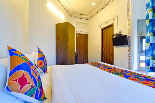 a bedroom with a large white bed with colorful pillows at FabExpress Achrol Palace in Udaipur