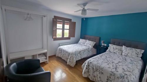 1 Schlafzimmer mit 2 Betten, einem Stuhl und einem Fenster in der Unterkunft Paredejas del Rey in Priego de Córdoba