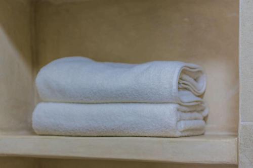 three towels are stacked on a shelf in a bathroom at Stella 3 - superbe appartement avec cheminée en médina in Essaouira
