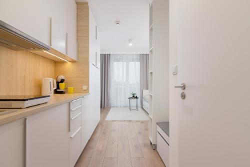 a kitchen with white cabinets and a door at Saska Blu Studio Apartments Podgórze by Renters in Krakow