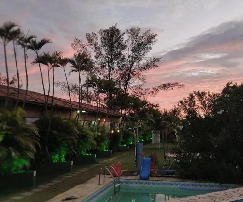 a swimming pool with a playground and palm trees at POUSADA ARKAN BEACH in Saquarema