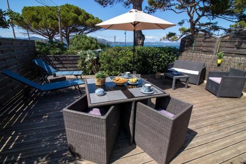une table et des chaises sur une terrasse avec un parasol dans l'établissement Le Bastidon, charmant studio 2 pers avec vue mer, idéalement situé, à Hyères