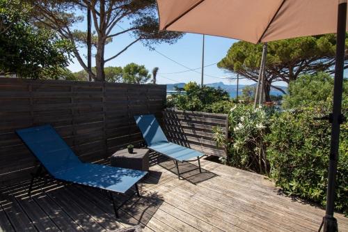 2 chaises bleues et un parasol sur une terrasse en bois dans l'établissement Le Bastidon, charmant studio 2 pers avec vue mer, idéalement situé, à Hyères