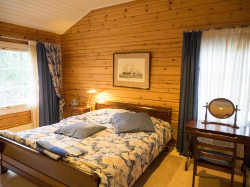 1 dormitorio con 1 cama y pared de madera en Villa Mustikka en Tammisaari