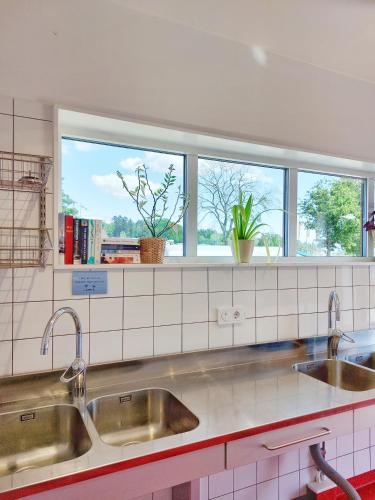 a kitchen with two sinks and two windows at Nävekvarns Skärgårdscamping in Nävekvarn