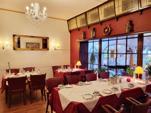 a dining room with tables and chairs and a chandelier at Hotel Columbus und Glamping in Bremerhaven