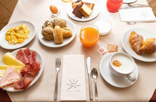 a table topped with plates of breakfast foods and orange juice at Santa Maria ad Nives in Canazei