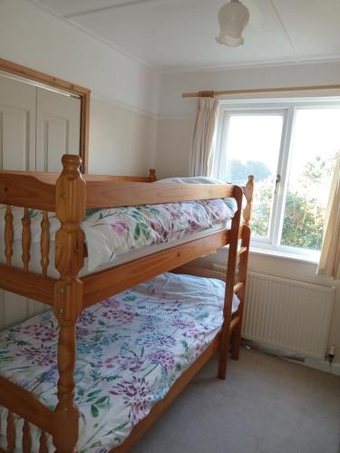 two bunk beds in a room with a window at Curlews Cottage - House with 3 bedrooms and garden - walking distance to the beach in Perranporth