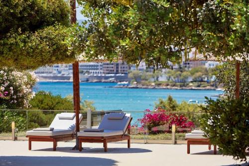 two chaise lounges on a patio with a view of the water at Vasia Ormos Hotel (Adults Only) in Agios Nikolaos
