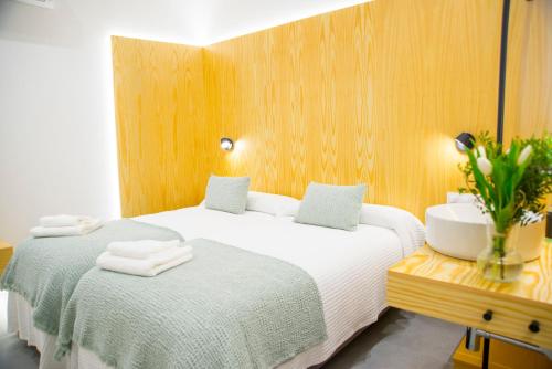 カルダス・デ・レイスにあるKALIDAS HOSTEL SUITESのベッドが2つと花瓶が置かれたホテルの部屋