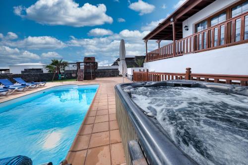 een zwembad met een hot tub op een patio bij Villa Flavia - Private Pool, Jacuzzi, BBQ and Game Room By Lanzarote Vacation Homes in Playa Blanca