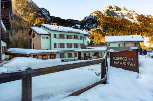 a sign in the snow in front of a lodge at Santa Maria ad Nives in Canazei