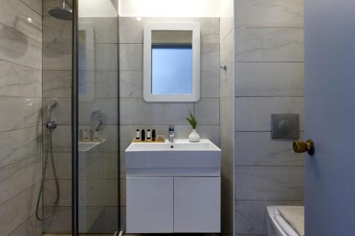 a bathroom with a sink and a shower with a mirror at Vasia Ormos Hotel (Adults Only) in Agios Nikolaos