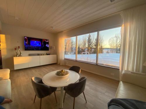 a living room with a table and chairs and a large window at Golden Circle private Farmhouse with hot tub in Selfoss
