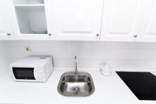 a kitchen with a sink and a microwave at AQUAMARINA A HomeStay By Turismar in La Pineda