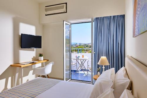 アギオス・ニコラオスにあるVasia Ormos Hotel (Adults Only)のベッド、デスク、バルコニーが備わるホテルルームです。