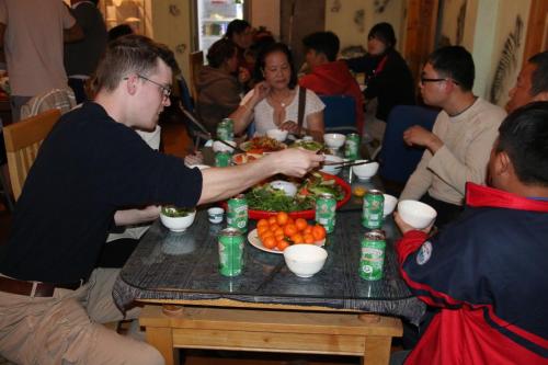 a group of people sitting around a table eating food at SaPa Farmer House in Sa Pa