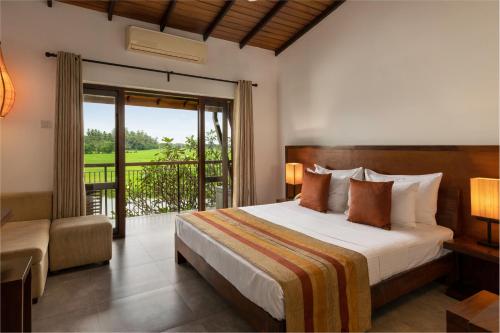 a bedroom with a bed and a balcony at Kithala Resort - Thema Collection in Tissamaharama