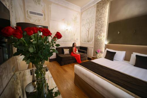 a woman sitting in a hotel room with a bed and roses at Santa Croce Boutique Hotel in Venice