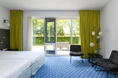 1 Schlafzimmer mit einem Bett, 2 Stühlen und einem Fenster in der Unterkunft Hotel De Roode Schuur in Nijkerk