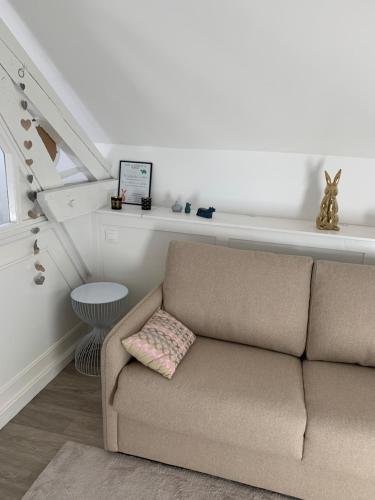 a couch in a living room with a white wall at Maison d'Hôtes Joussaume Latour in Château-Thierry