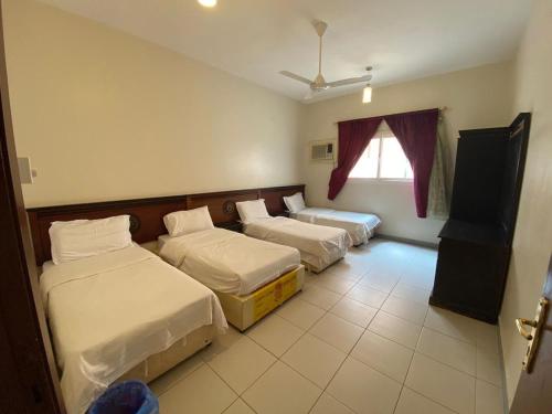 a hotel room with three beds and a window at منتجع وردة الهدا in Al Hada