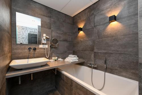 a bathroom with a sink and a bath tub at Hotel De Roode Schuur in Nijkerk
