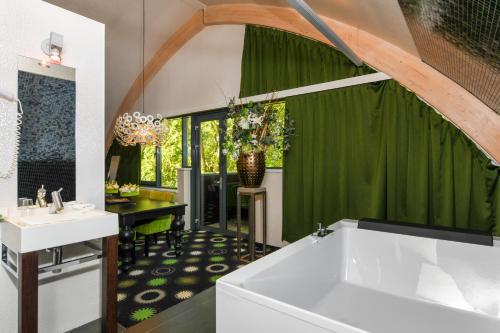 a bathroom with a white tub and a green curtain at Hotel De Roode Schuur in Nijkerk