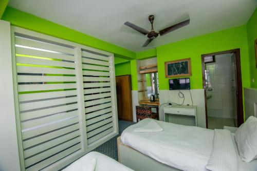 a bedroom with green walls and a bed and a bathroom at Hotel Pomelo House Inn in Kathmandu