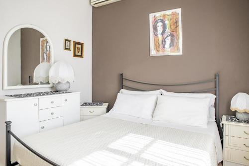 a white bedroom with a bed and a mirror at Villa Lucia in Ognina