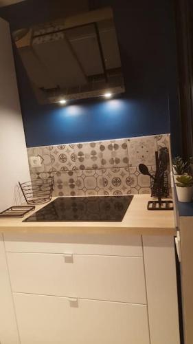 - une cuisine avec une cuisinière et un mur bleu dans l'établissement Logement tout neuf avec piscine et bord de mer, à Canet